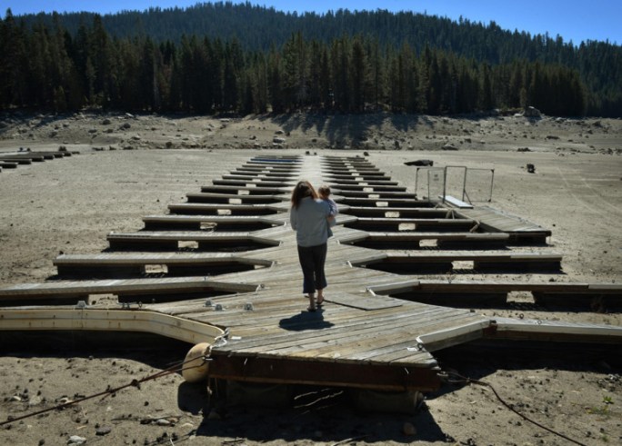 Marina owner Mitzi Richards carries her granddaughter as they walk on their boat dock at the dried up lake bed of Huntington Lake which is at only 30 percent capacity as a severe drought continues to affect California on September 23, 2014.  California is in the grip of its third year of severe drought, the worst in decades, threatening to drain underground aquifers and leaving the taps of some 40 million people to run dry. The state's drought affected Central Valley, is the  considered the richest food-producing region in the world, where much of America's fresh fruits, nuts and vegetables being grown there.            AFP PHOTO/Mark RALSTON        (Photo credit should read MARK RALSTON/AFP/Getty Images)